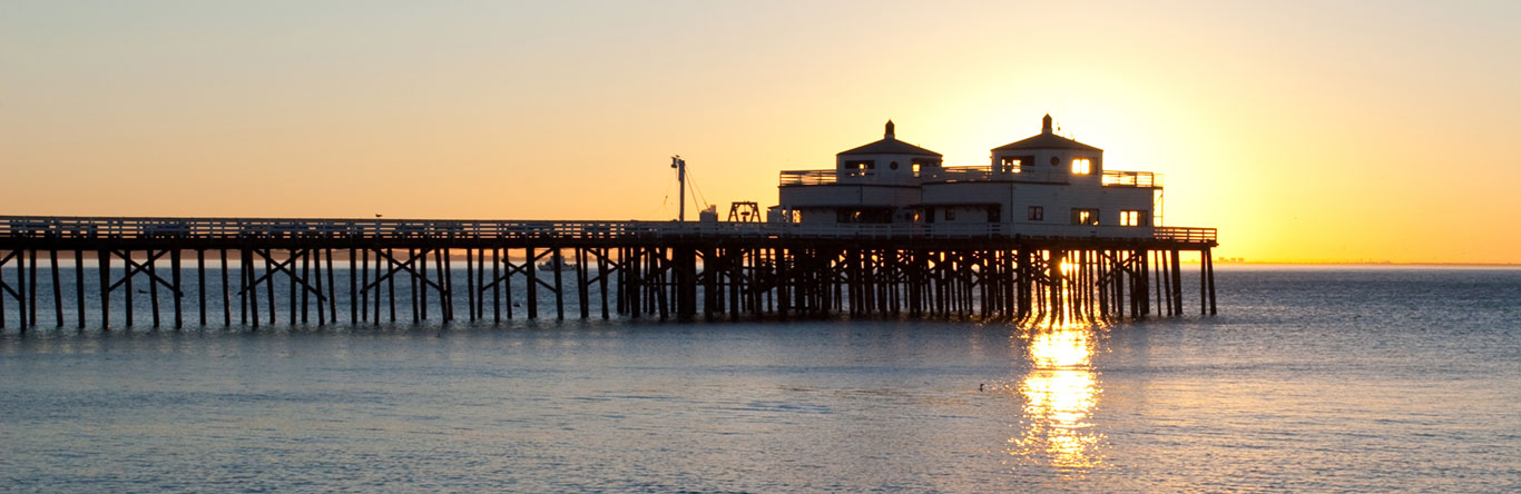 End of pier over ocean at sunset